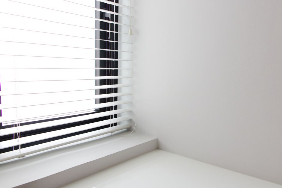 Expert measuring a window for custom blinds and drapes